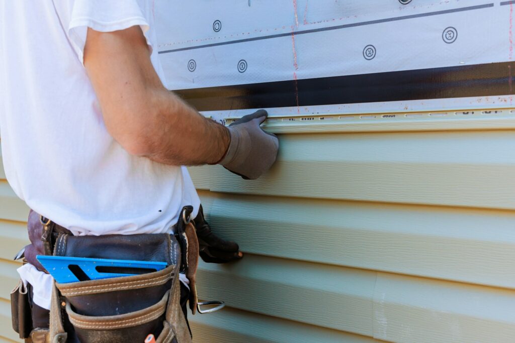 Handyman process installing vinyl PVC siding during construction on a facade new home