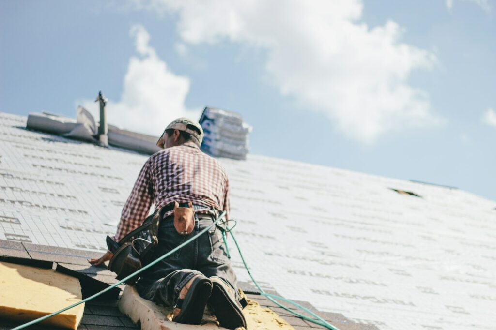 Roofer adding shingles to the roof of a house